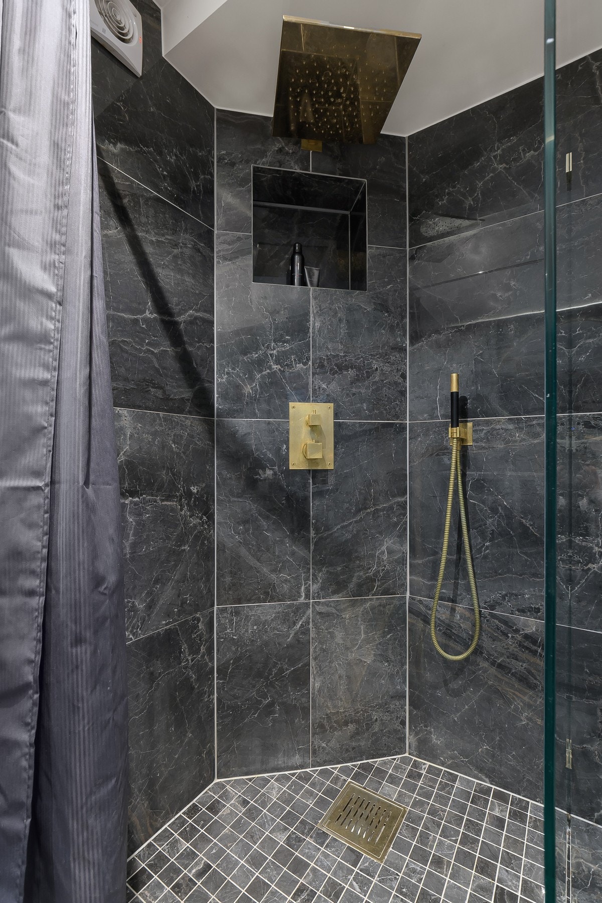 Dusjsone med takdusj og flott detaljer i gullfinish - mørke fliser og nisje i vegg gir et eksklusivt og spa-inspirert uttrykk. Galleribilde