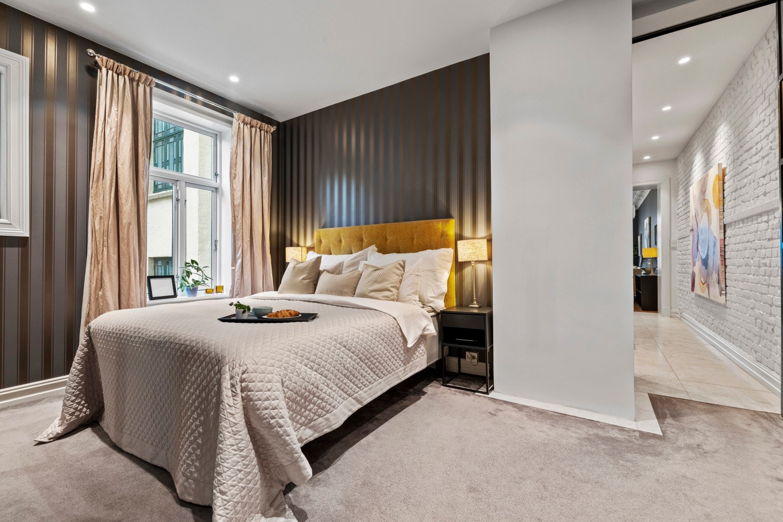 Hovedsoverommet er lunt og tilbaketrukket med helhetlige fargetoner, vegg-til-vegg-teppe og behagelig belysning fra downlights. Galleribilde