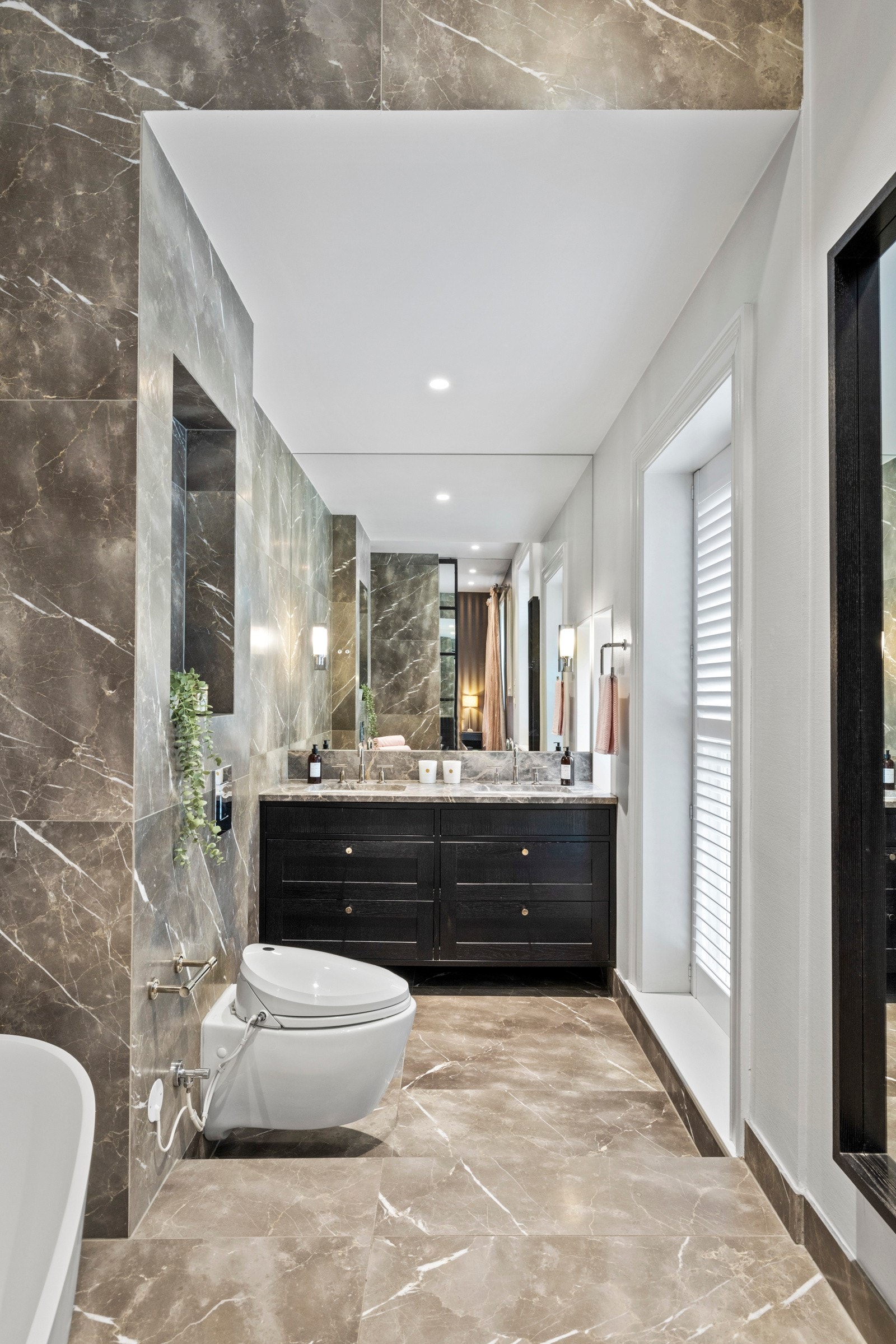 Innredningen består av to servanter underlimt i steinplate med tilhørende servantskap, vegghengt toalett med skjult sisterne, samt et frittstående designbadekar med gulvmontert armatur. Galleribilde