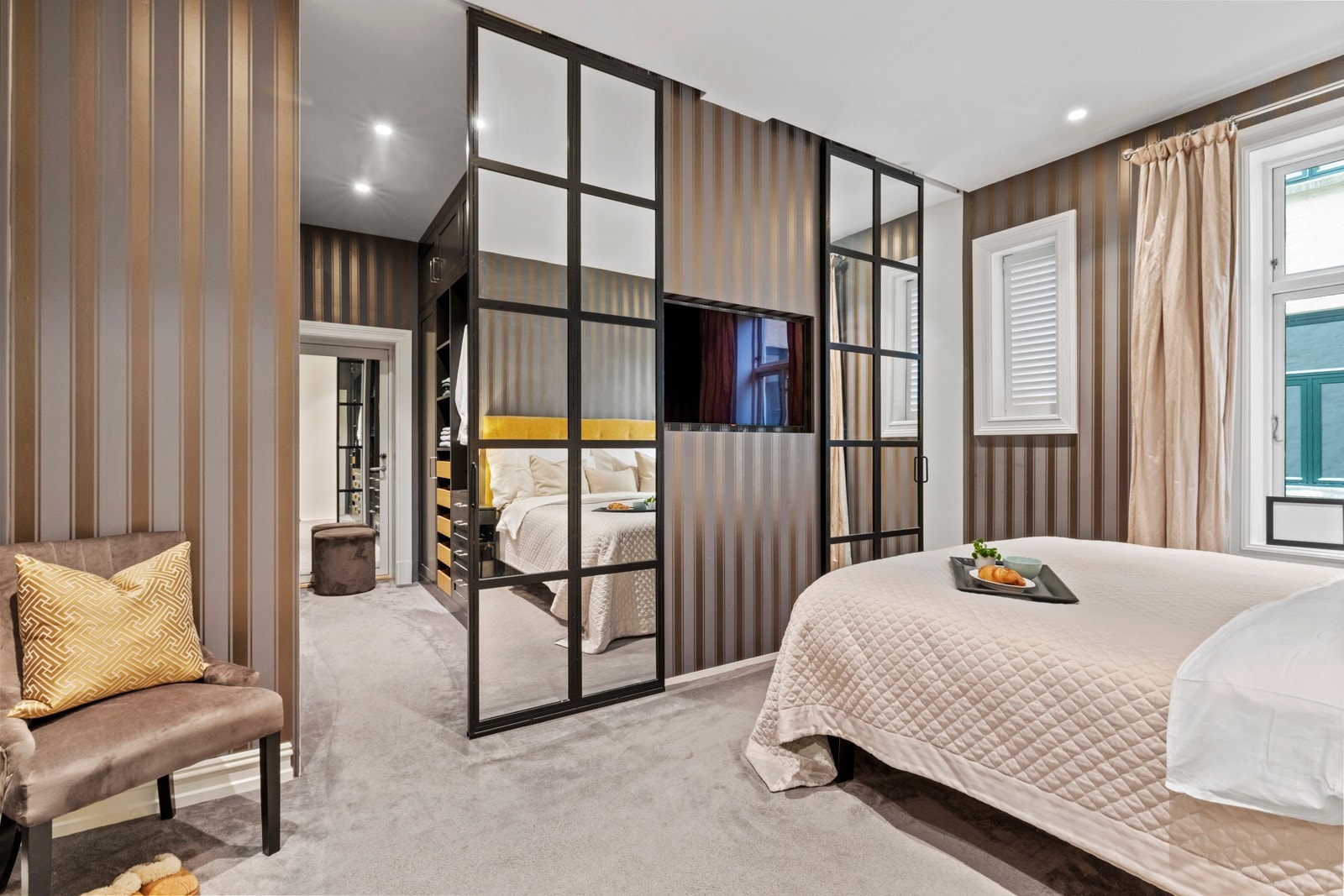 Rommet har god plass til dobbeltseng og tilhørende møblement, og er tilknyttet både eget walk-in closet og hovedbad, noe som gir en eksklusiv og funksjonell suitefølelse. Galleribilde