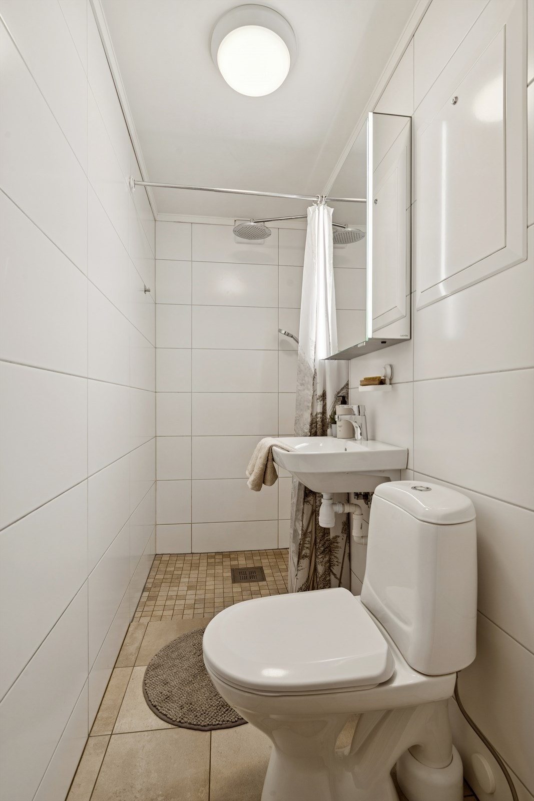 Baderom med fliser på vegg og gulv med sparklet og malt himling. Galleribilde