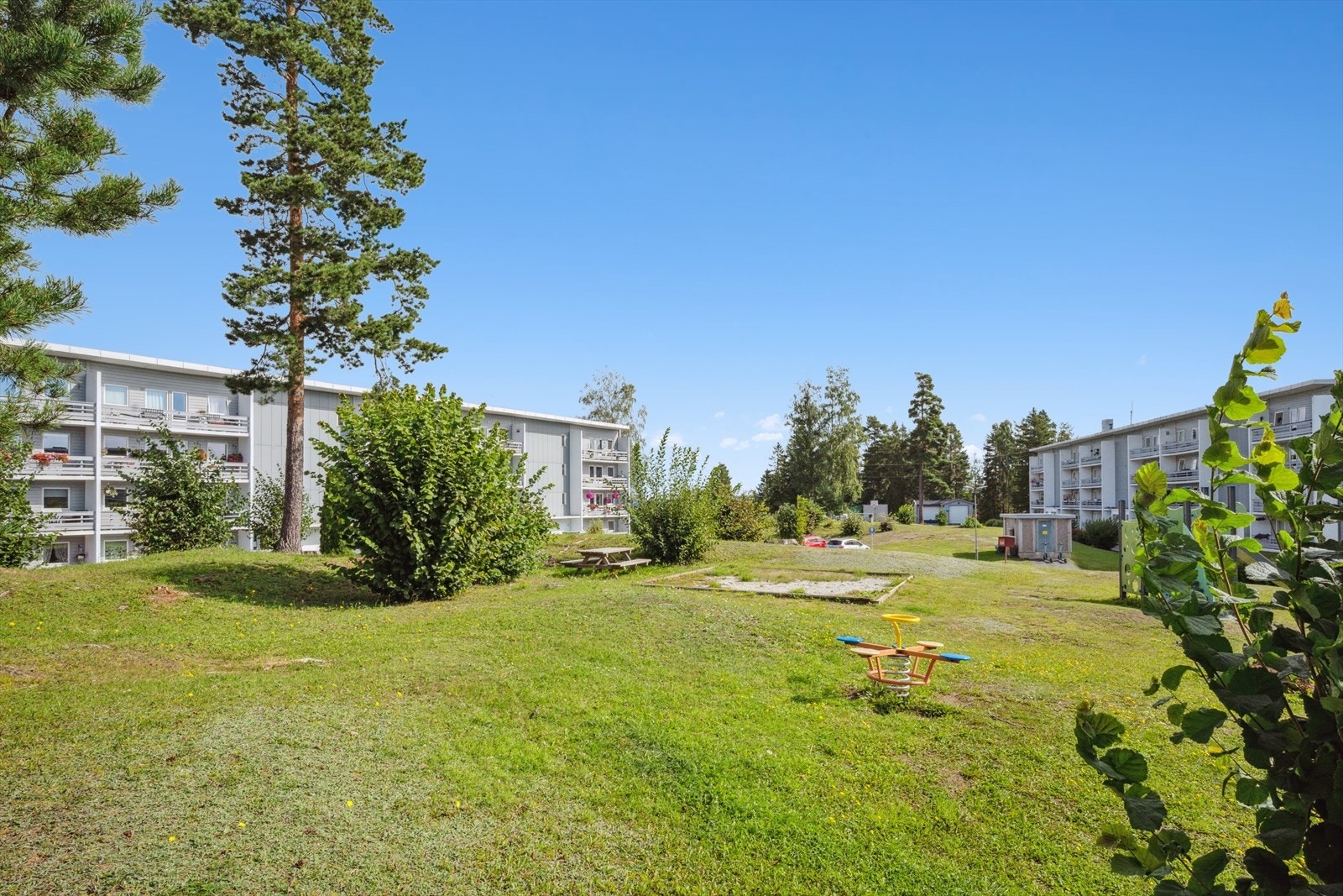 Pent opparbeidet felles tomtegrunn med asfalterte gang- og kjøreveier, parkeringsplasser, lekeapparater for barn, plenarealer og beplantning. Galleribilde