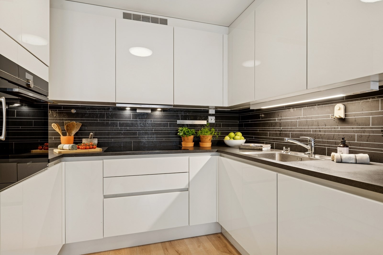 Lekkert kjøkken med kjøkkeninnredning med fronter i høyglanset utførelse. Galleribilde