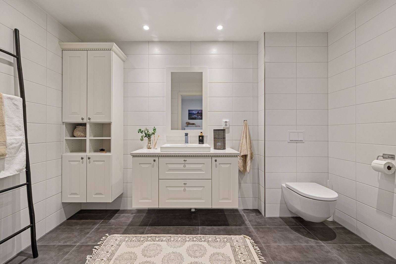 Lekkert flislagt bad. Innredning med nedfelt servant, veggmontert toalett, dusjvegger/hjørne og opplegg for vaskemaskin. Galleribilde