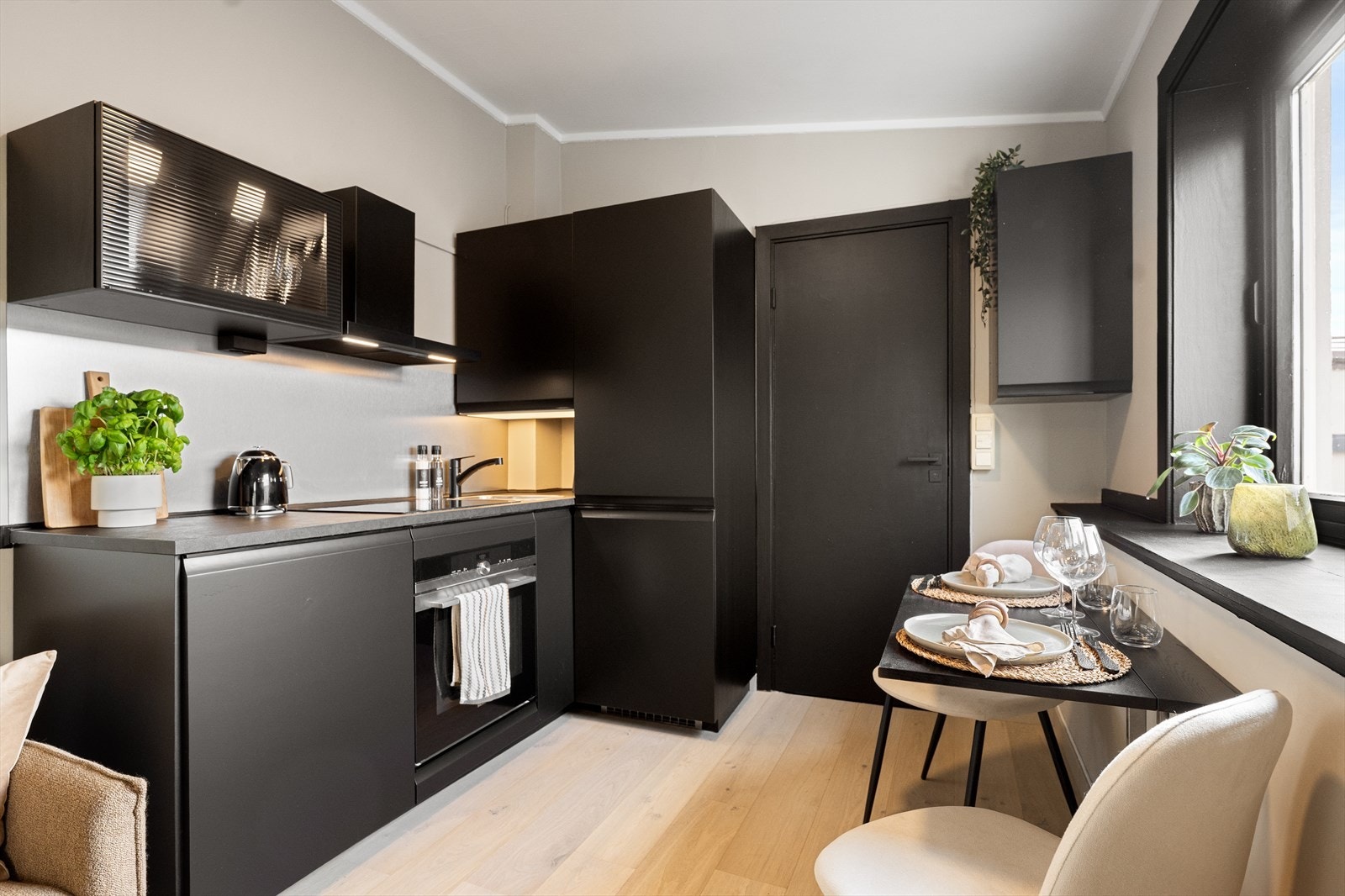 Innredning med slette fronter i sort utførelse og laminert benkeplate med nedfelt vaskekum. Galleribilde