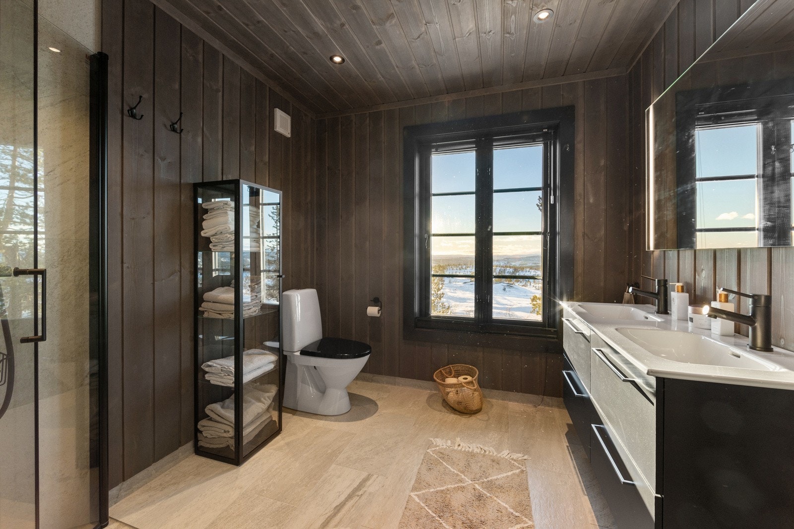 Badet har flislagt gulv og fliser i dusjsonen, mens øvrige vegger og himling er utført med panel som gir et varmt og helhetlig uttrykk. Galleribilde