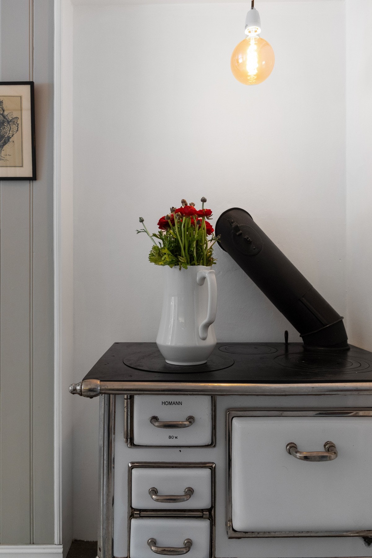 En emaljert, vedfyrt kjøkkenovn står som et dekorativt innslag og understreker den landlige atmosfæren. Galleribilde