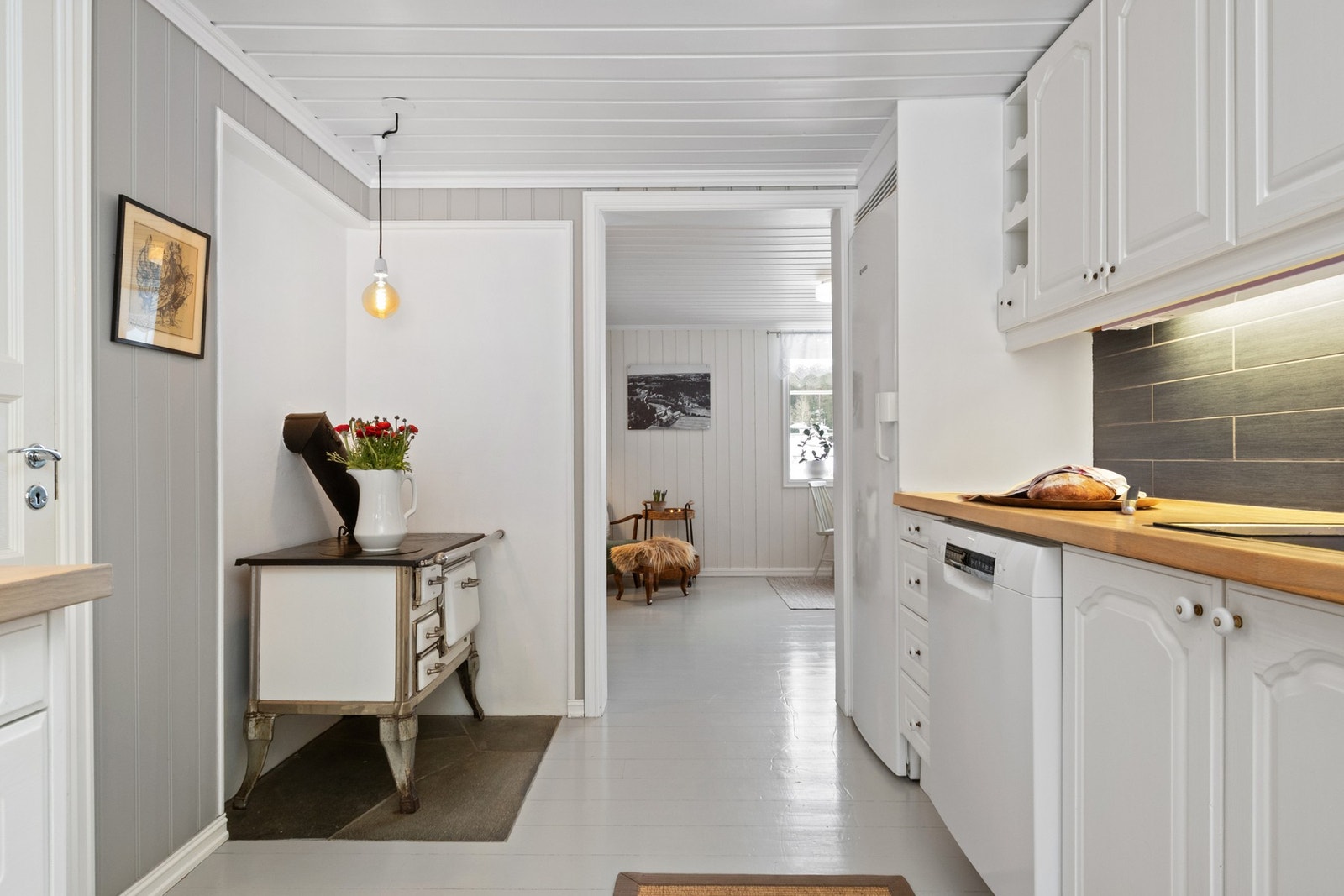 Her er det tregulv og panelvegger malt i duse gråtoner, og overflatene videreføres inn i en separat spisekrok som legger til rette for hyggelige måltider Galleribilde