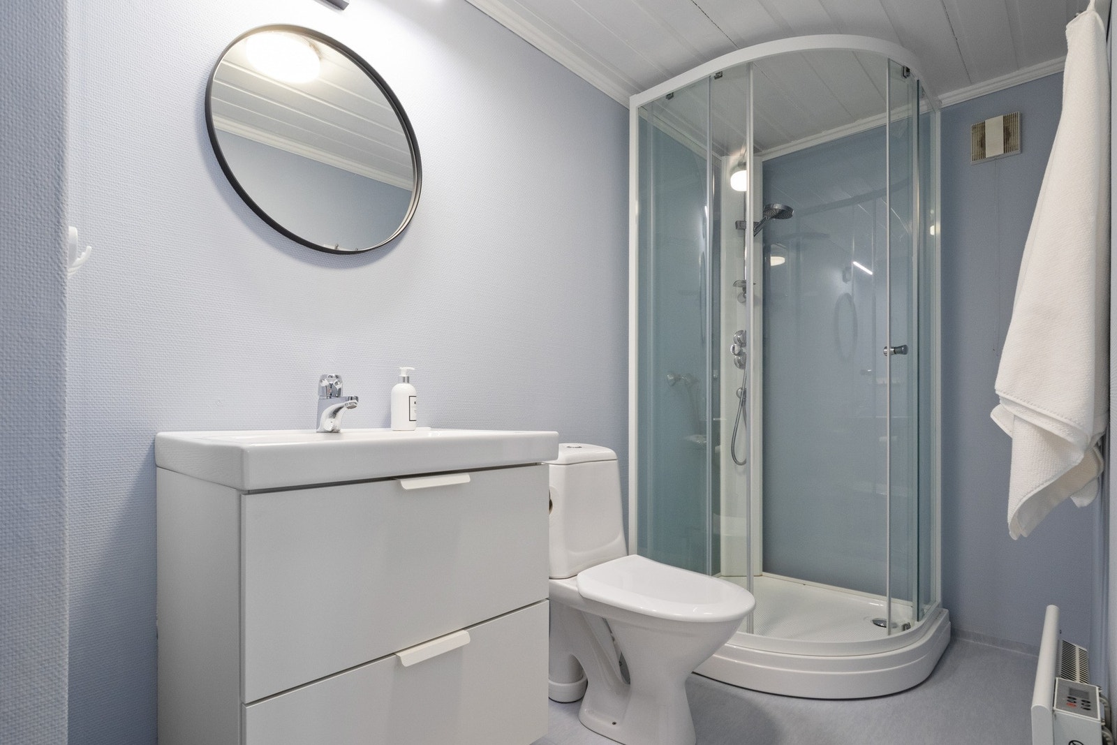 Badet i 1. etasje ligger i tilknytning til soverom og har vinylbelegg på gulv samt vegger malt i en pastellblå tone. Galleribilde