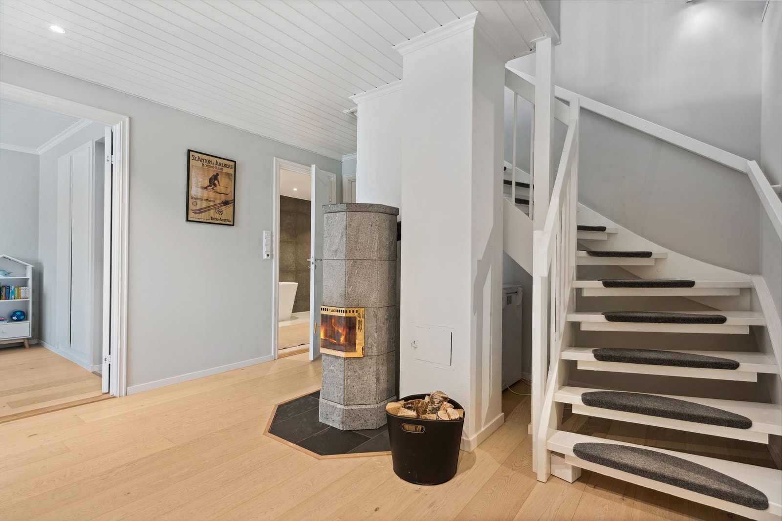Nede i underetasjen møter vi et romslig trapperom. Her er det en flott klebersteinsovn som gir lun varme til hele boligen. Galleribilde