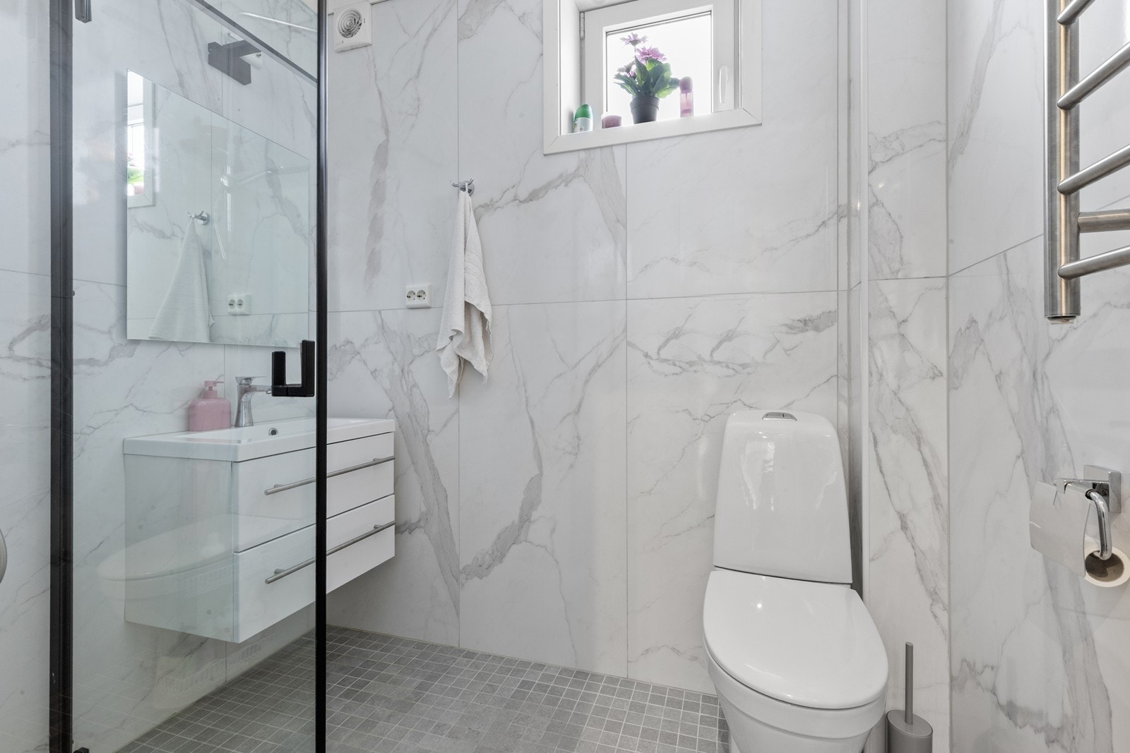 Pent flislagt bad med dusjhjørne, toalett og servant med lagringsplass Galleribilde