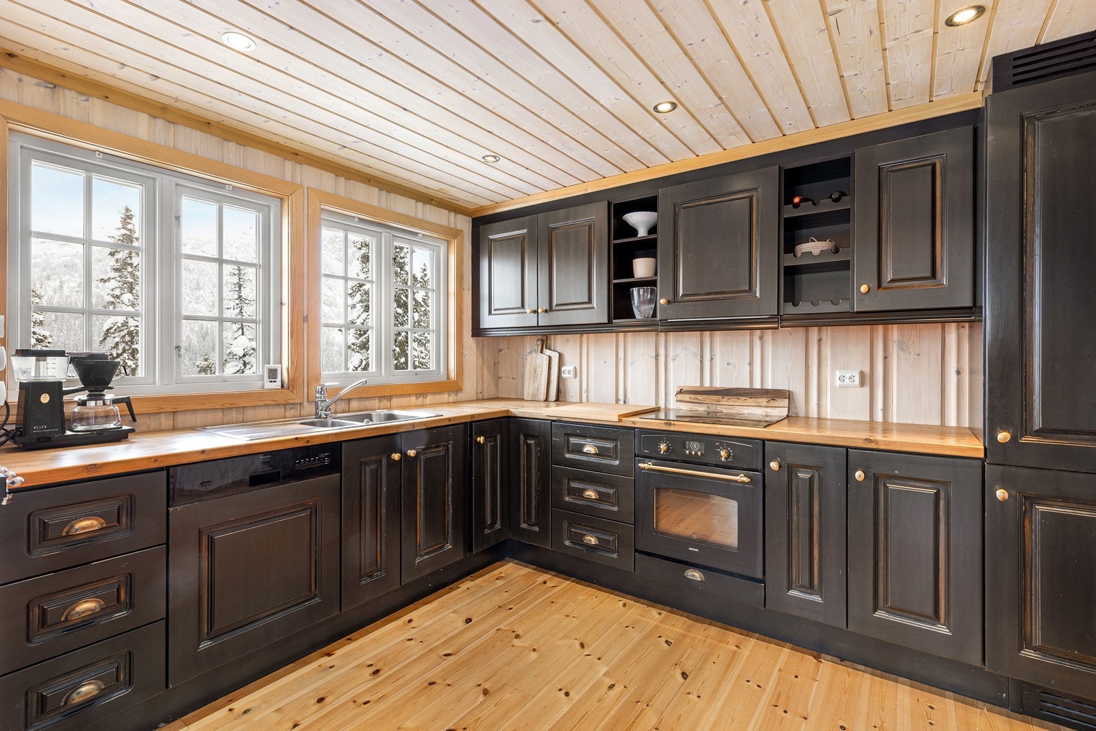 Romslig kjøkken med aldringsmalte fronter, heltre benkeplate og integrerte hvitevarer. Galleribilde