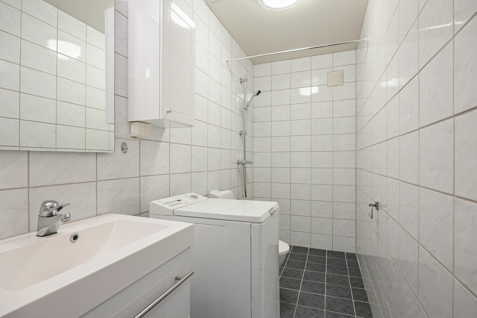 Badet i hybelen har nedfelt servant, toalett, dusjhjørne med dusjforheng og opplegg for vaskemaskin. Veggene og gulvet har fliser og det er behagelig varme i gulv. Galleribilde