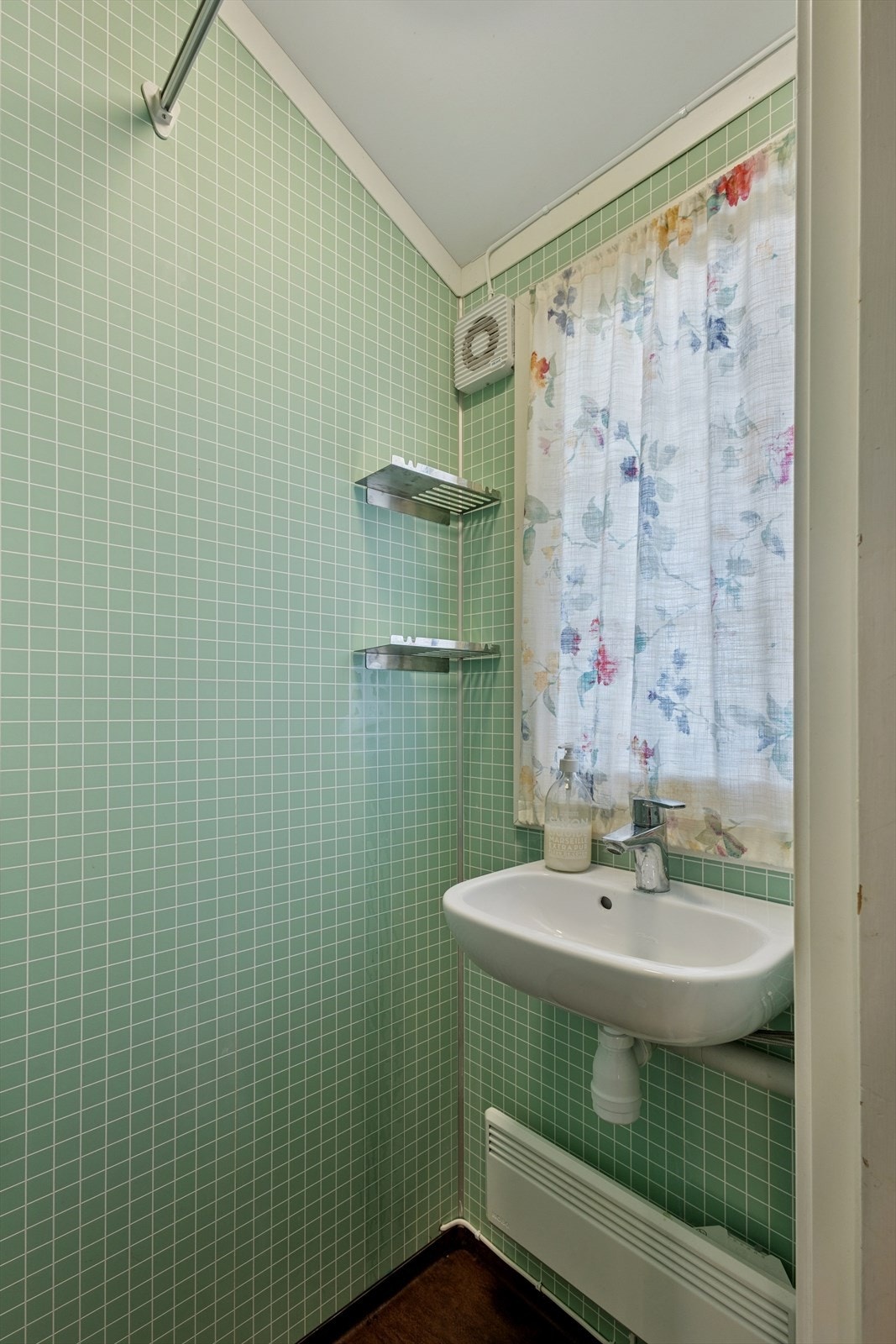 Badet har belegg på gulvet, baderomsplater på veggene og panel i himlingen. Rommet er utstyrt med en dusjnisje og en servant. Galleribilde