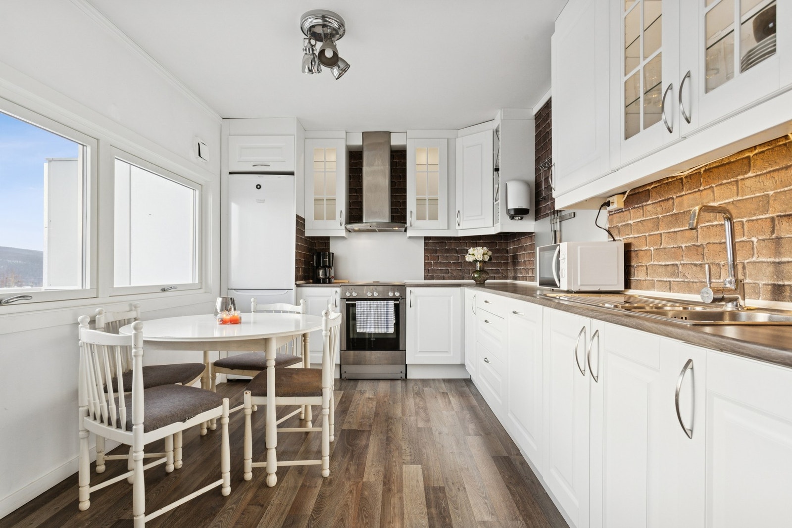 Lyse profilerte fronter med med glass i overskapene og plasstilpasset for frittstående hvitevarer. Galleribilde