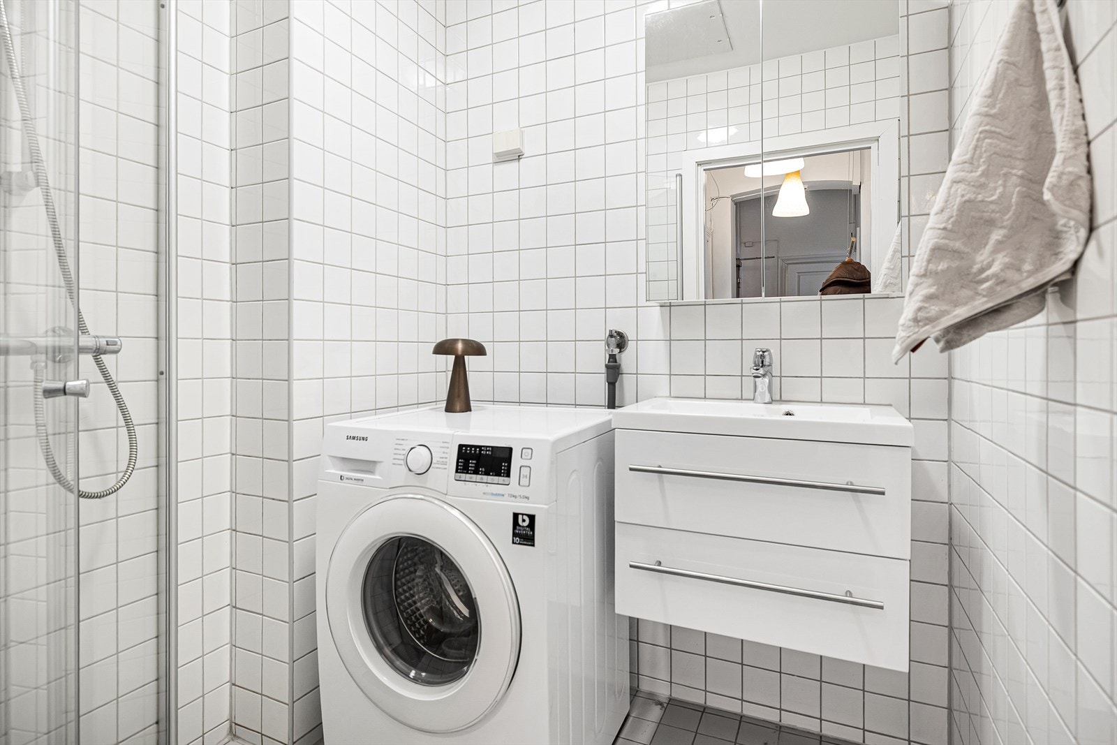 Bad med flislagte overflater og servantinnredning - funksjonelt og lettstelt. Opplegg for vaskemaskin gir en praktisk hverdag, og planløsningen utnytter arealet godt. Galleribilde