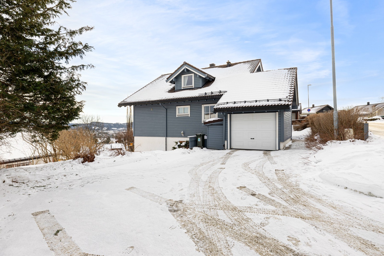 Boligen har en garasje med installert lader for elbil og gode parkeringsmuligheter for flere biler på tomt. Galleribilde