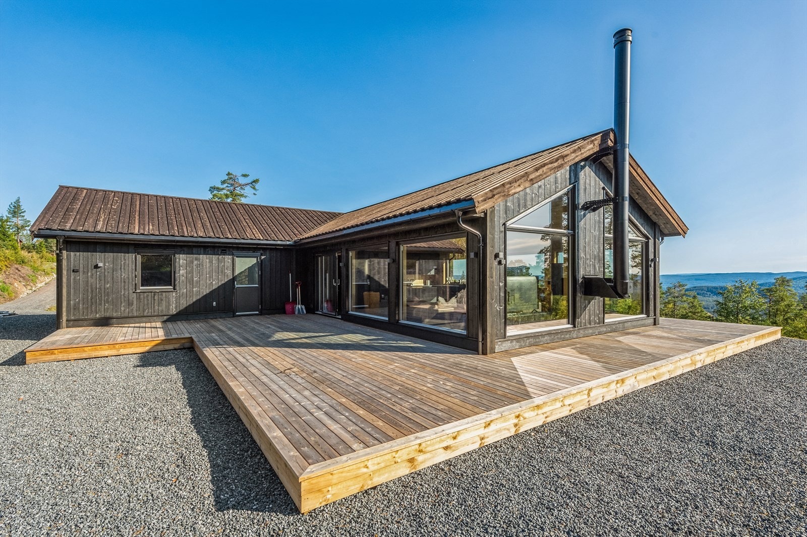 Stor terrasse som strekker seg rundt store deler av hytta Galleribilde