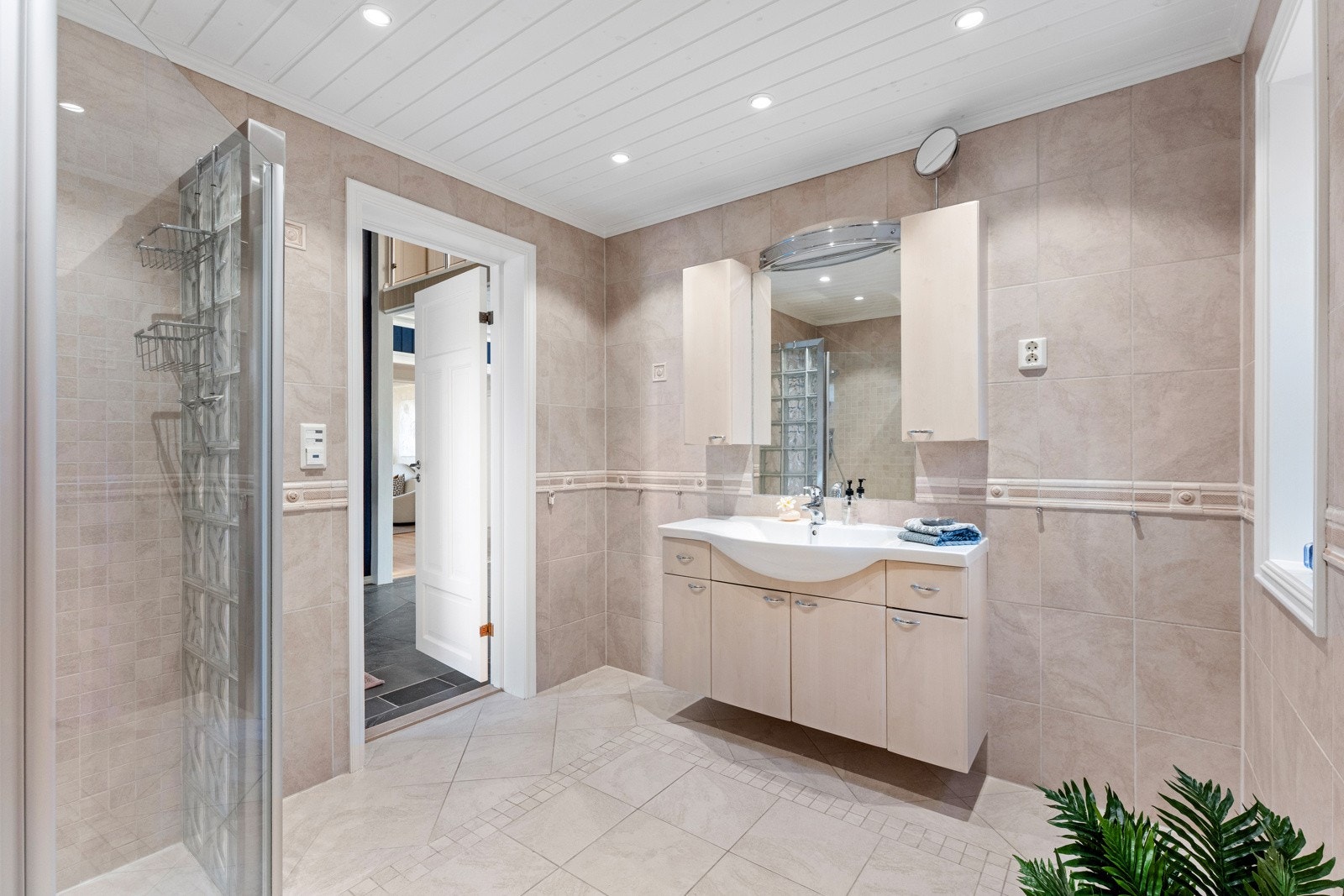 Badet i første etasje har flislagte vegger og gulv, samt malt himling med downlights Galleribilde