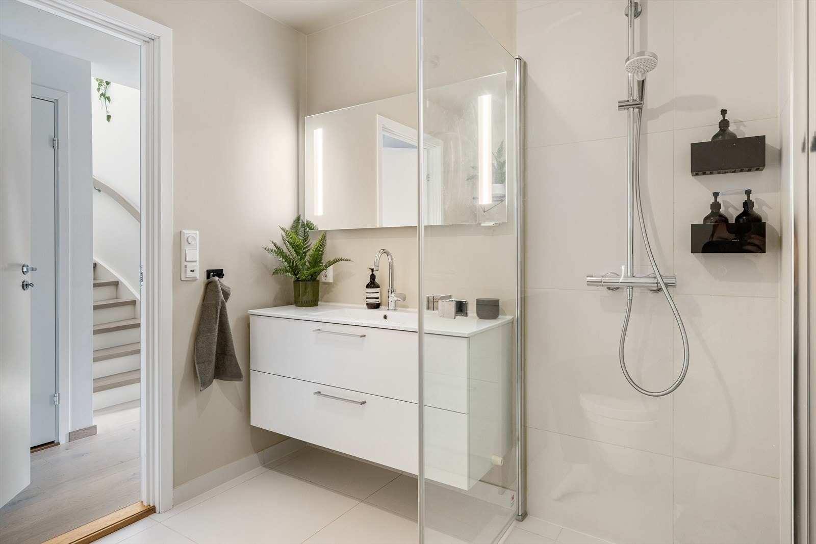 Badet har dusj på vegg med glassdører, helstøpt servant i skuffeseksjon, vegghengt toalett og opplegg for vaskemaskin. Galleribilde