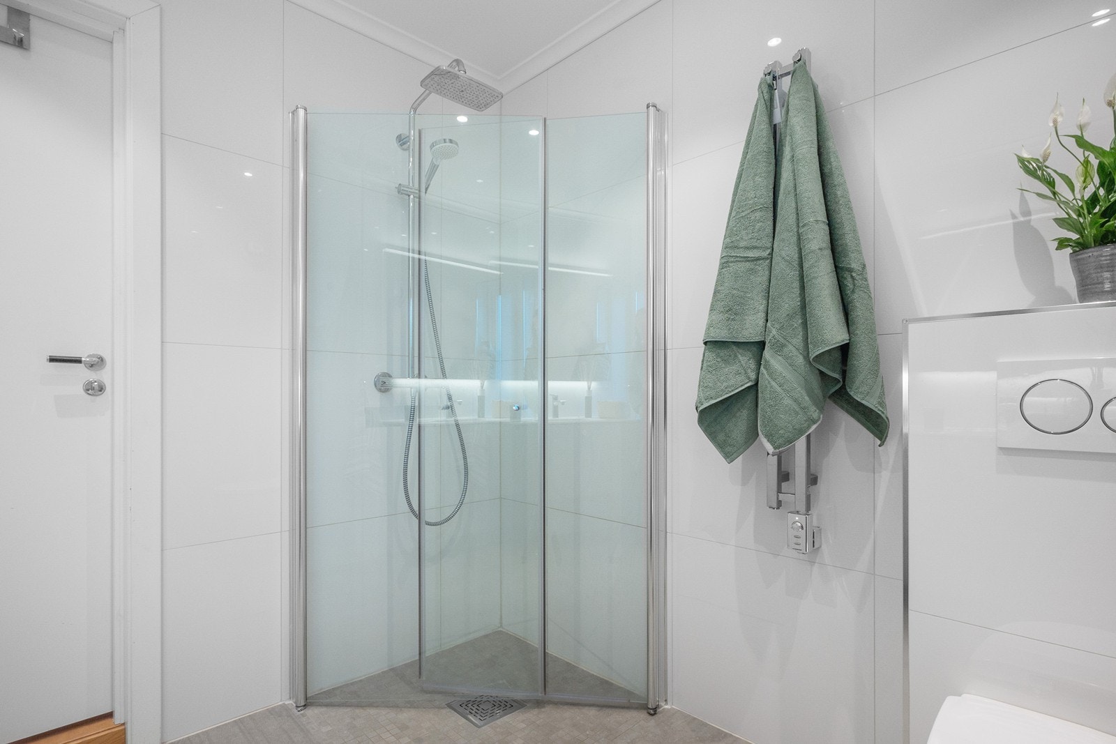 Her er det vegghengt toalett, håndkletørker og dusjhjørne med innfellbare glassdører, tak- og hånddusj. Galleribilde