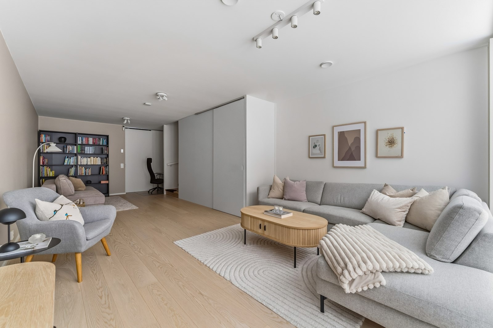 Lyse veggflater kombineres med 1-stavs parkettgulv, og utformingen gjør stuen enkel å møblere med flere sittegrupper. Galleribilde