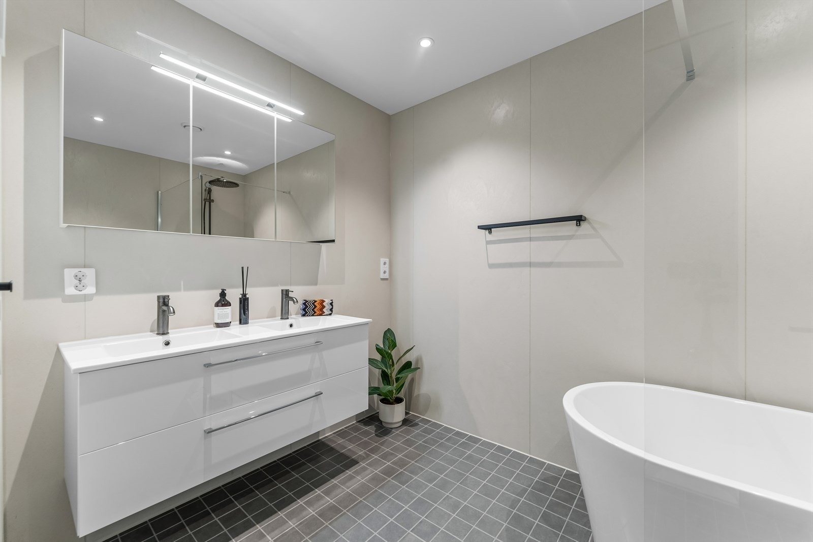 Baderomsinnredningen består av dobbel servant med hvite skuffer og et stort speilskap med belysning. Galleribilde