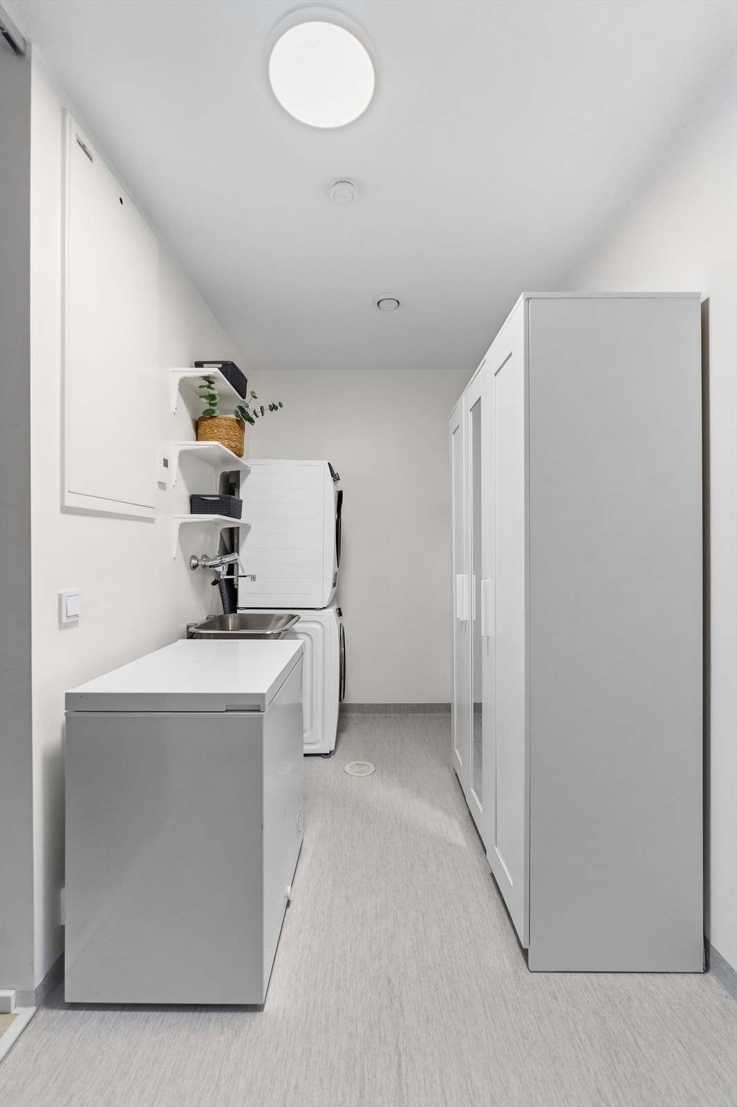 Eget praktisk vaskerom med skyllekum, åpne hyller og vinylbelegg med varme. Galleribilde