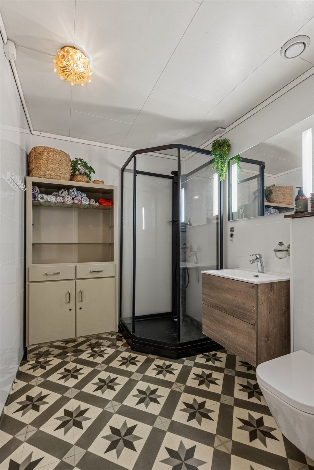 Lyst og pent bad innredet med dusjkabinett og vegghengt toalett. Galleribilde