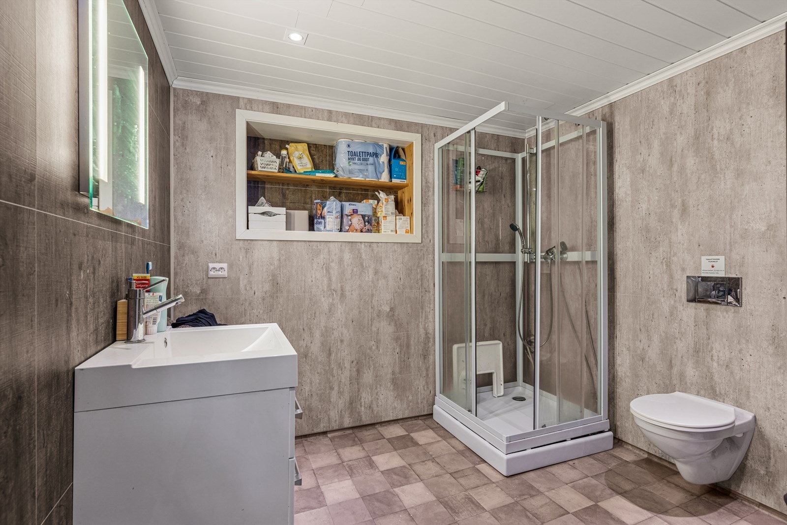 Bad/vaskerom utstyrt med dusjkabinett, vegghengt toalett og moderne baderomsinnredning. Galleribilde