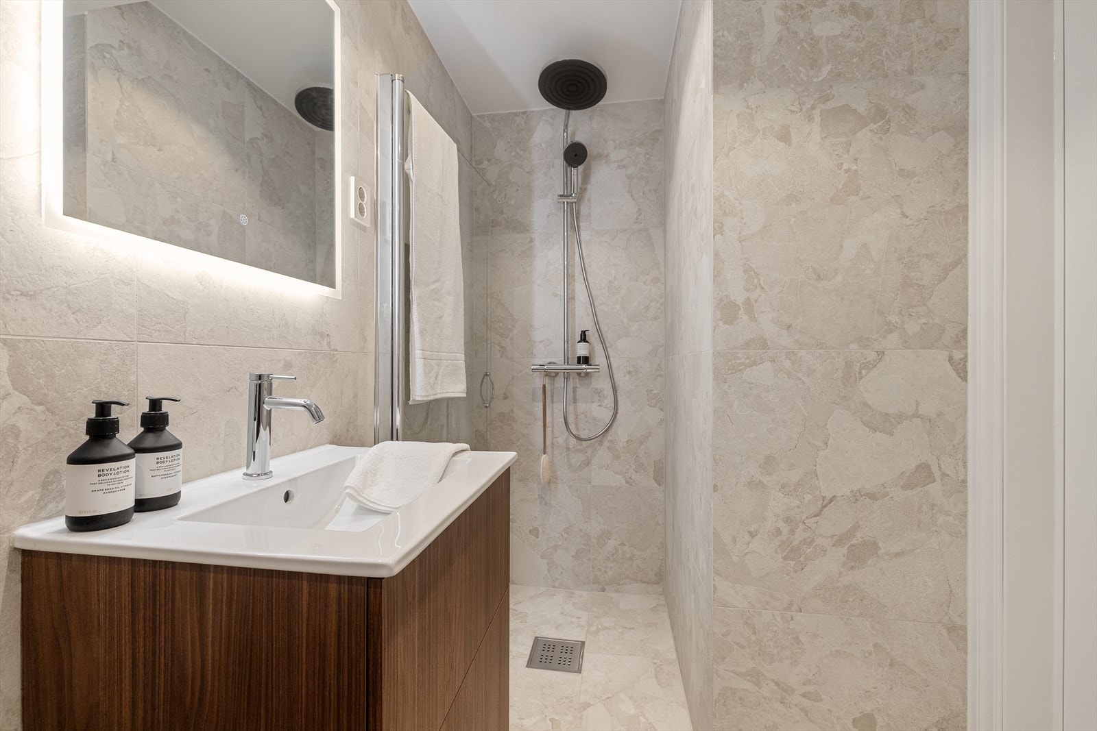 Innredning bestående av vegghengt toalett, servant med skuffer og dusjhjørne med glassdør. Galleribilde