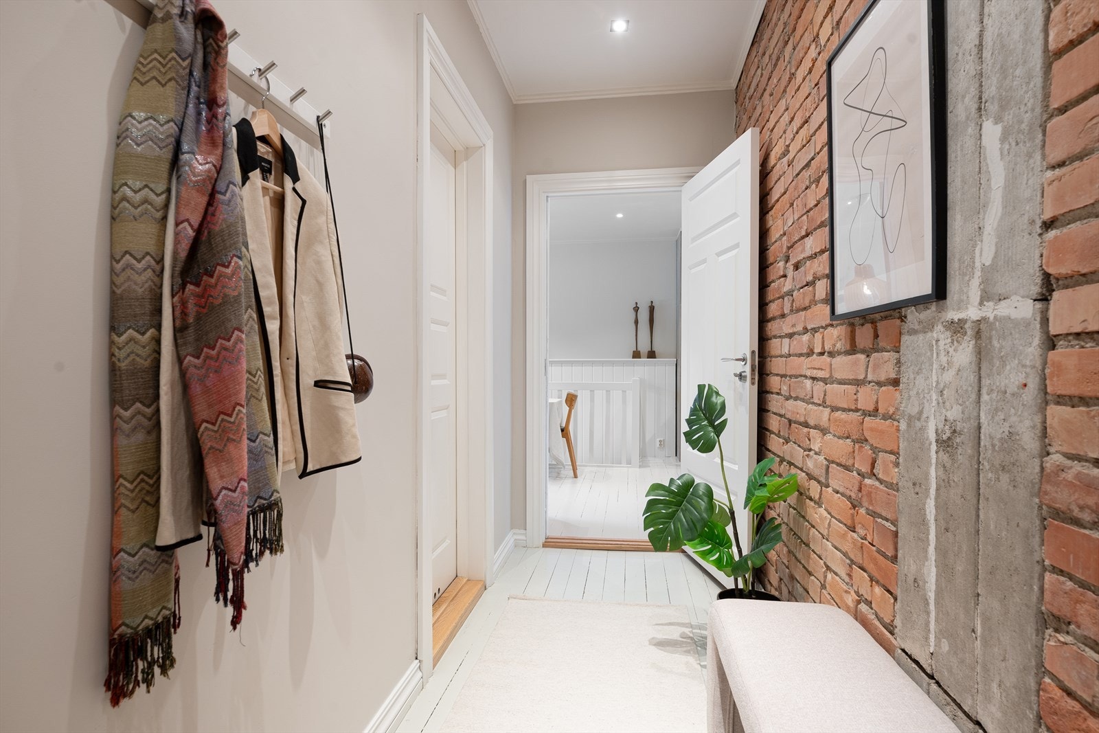 Straks man trer over dørterskelen åpenbarer leilighetens særpreg seg med bl.a. den rustikke teglsteinsveggen Galleribilde