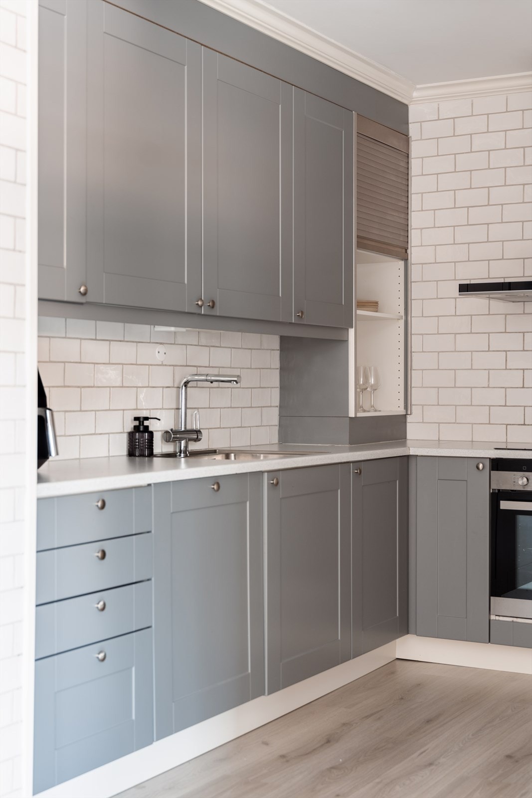 Kjøkkeninnredningen har glatte, grå fronter og en slitesterk, lys laminatbenkeplate. Galleribilde