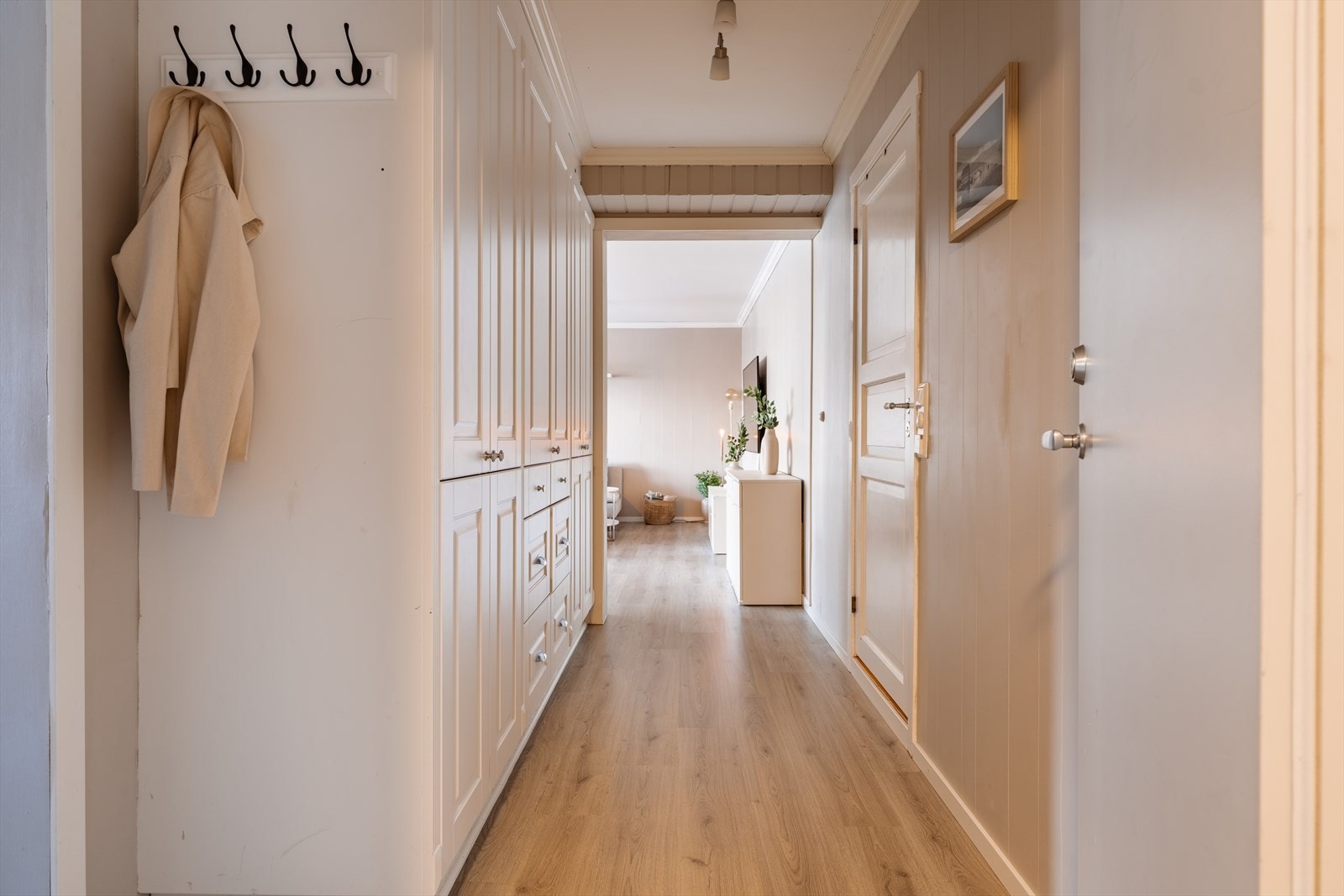 Gangen har gjennomgående laminatgulv og leder videre inn til leilighetens oppholdsrom. Galleribilde