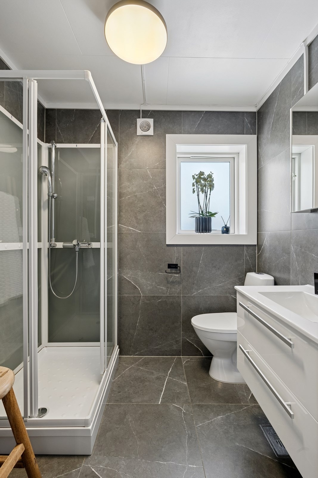 Badet er pent helfliset med varmekabler i gulvet, og er utstyrt med dusjkabinett, servant og toalett - en god plass å starte dagen. Galleribilde