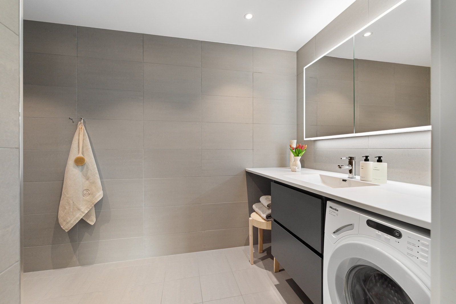 Badet har en praktisk innredning med skuffeløsning, heldekkende servant med ettgreps blandebatteri samt speilskap med integrert belysning. Galleribilde