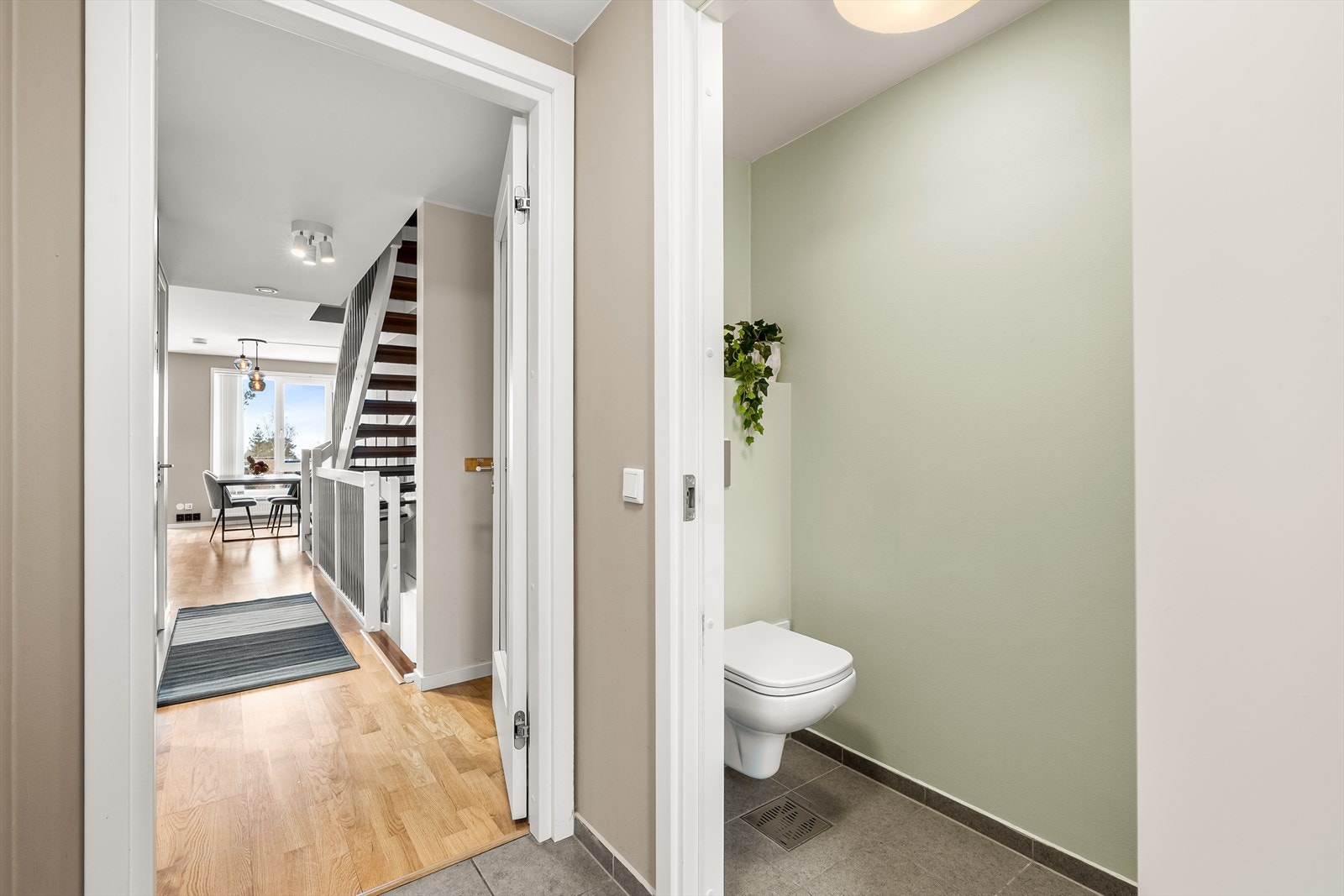 Toalettrom med adkomst fra vindfang, innredet med vegghengt klosett, innredning med glatte folierte fronter, heldekkende servant og speil på vegg over servanten. Galleribilde