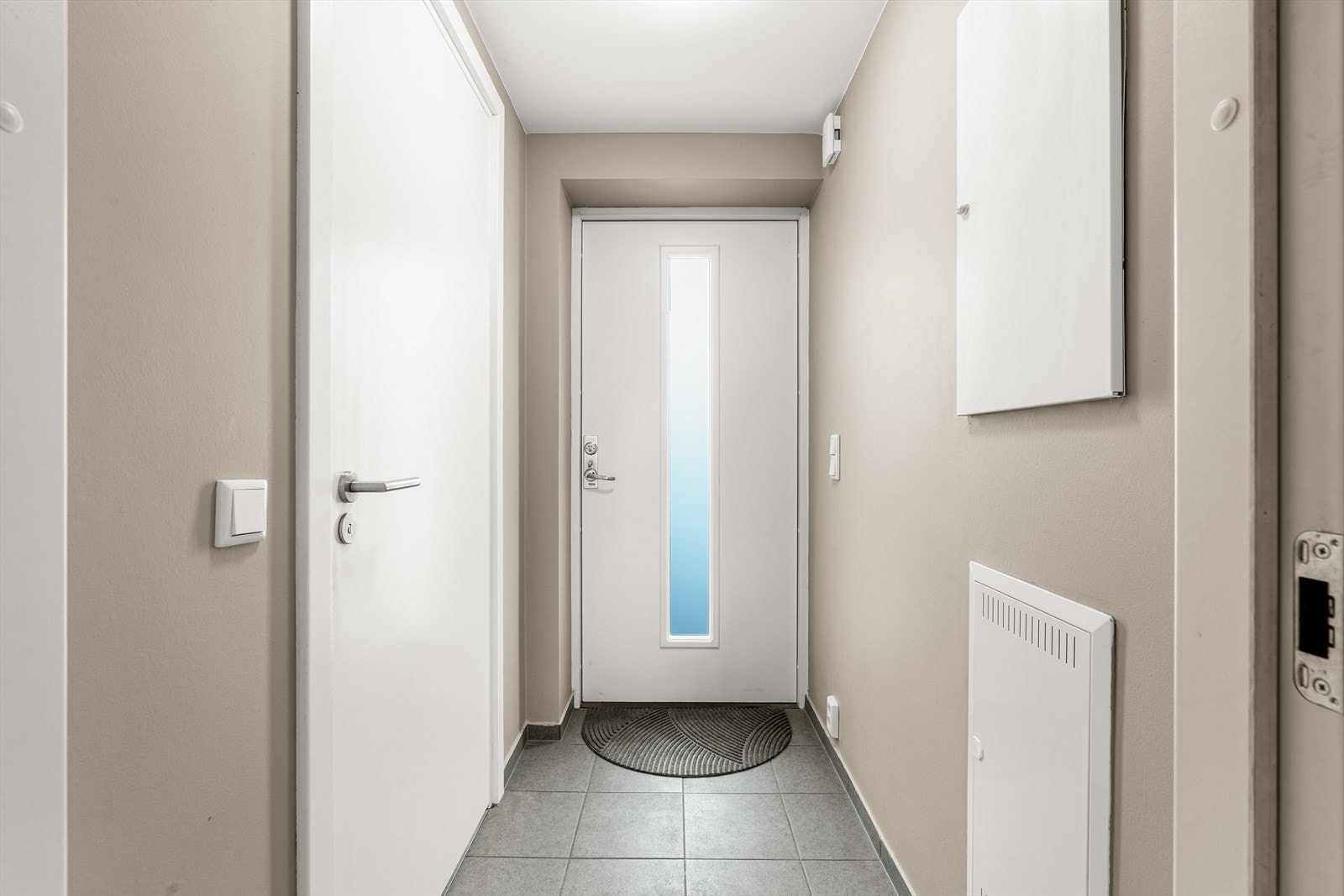 Innenfor inngangsdøren møtes man av en flislagt gang med vannbåren gulvvarme. Her er det sette fra seg sko. Galleribilde