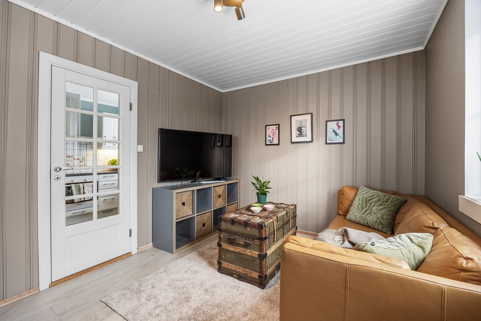 Rommet har en kombinasjon av trepanel og malte flater, med laminat på gulvet. Galleribilde