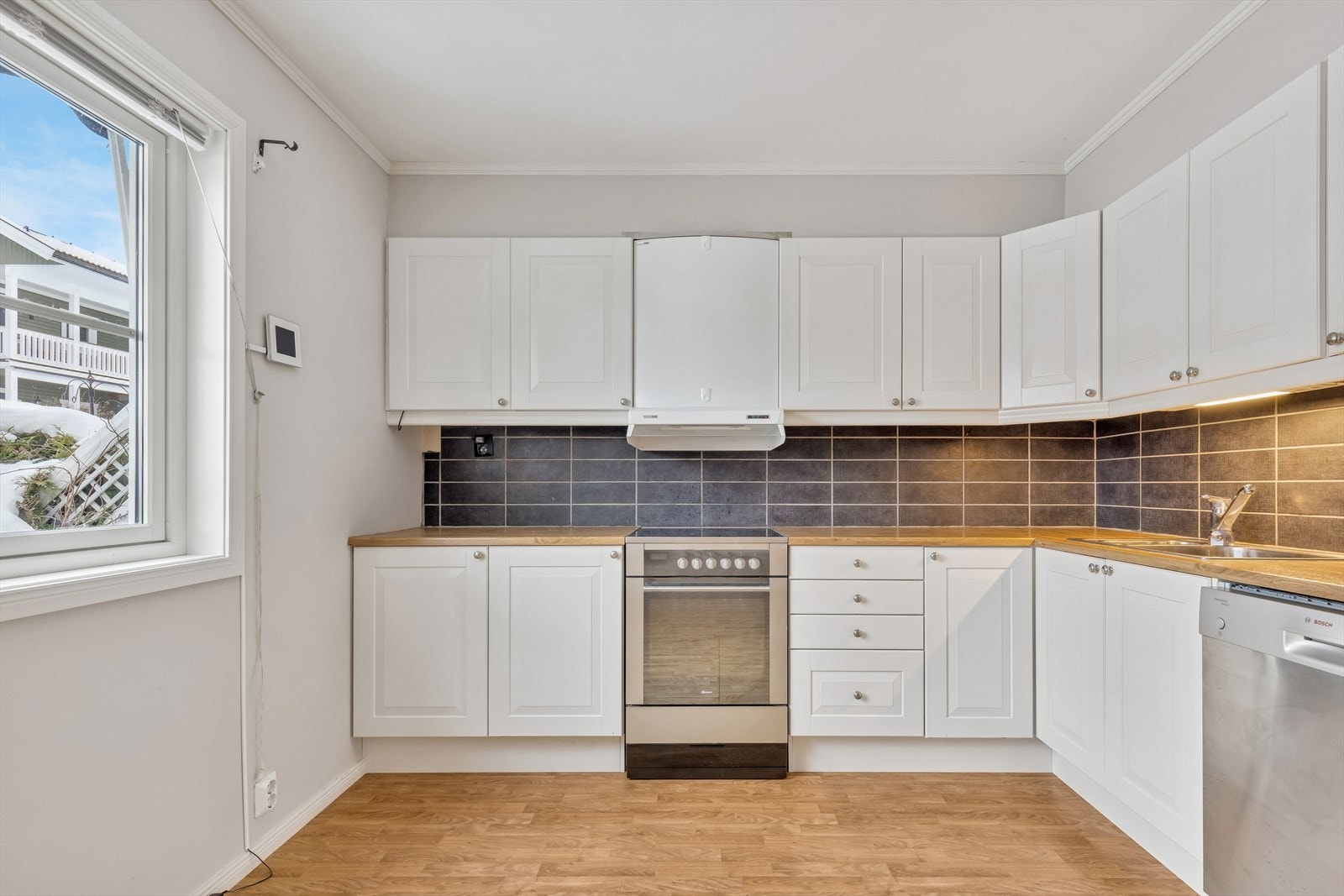 KjøkkenInnredningen har laminat benkeplate og fliser over benk Galleribilde