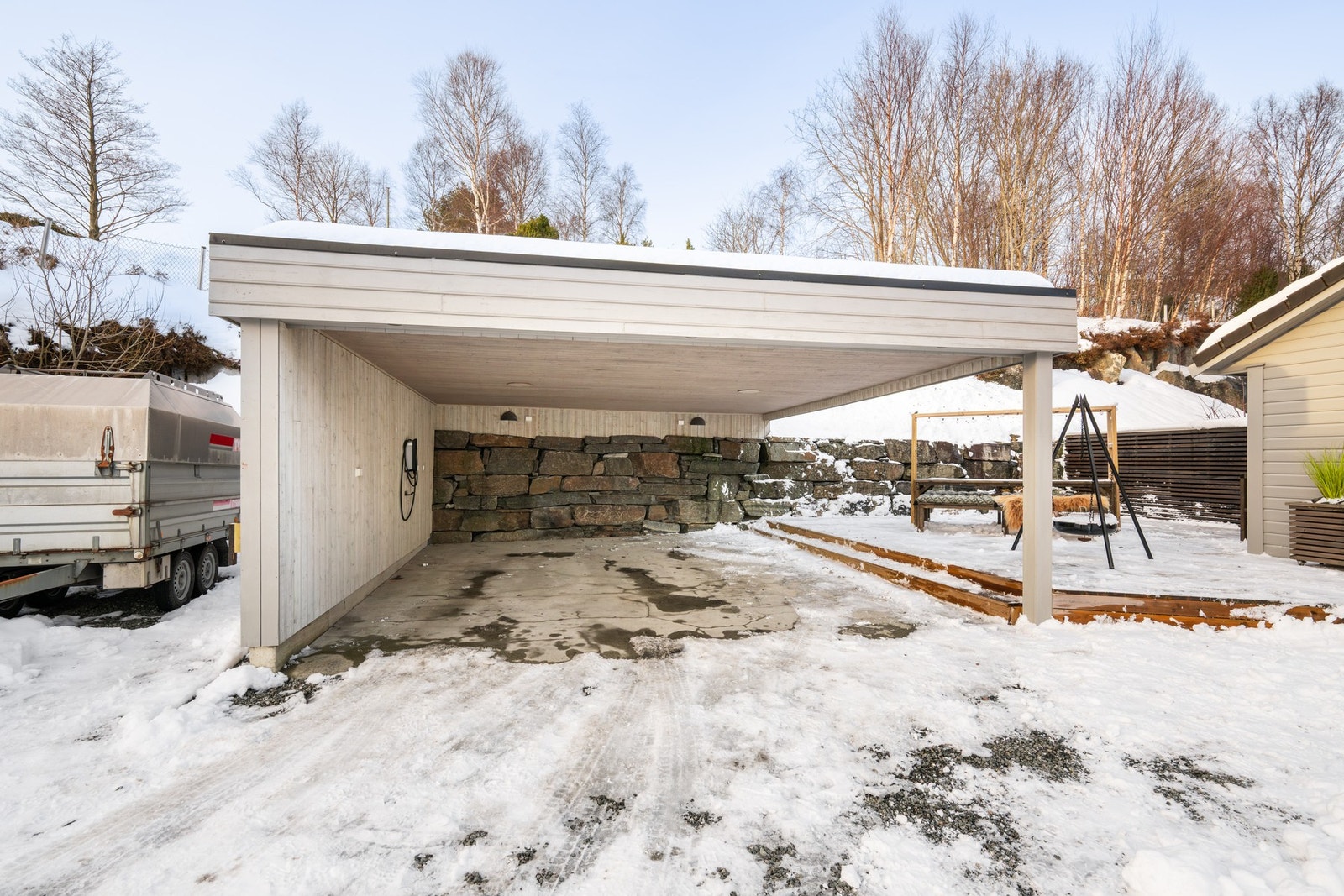 Dobbel carport og pent opparbeidet gårdsrom med grus og belegningsstein. Usjenert terrasse og utvendig bod Galleribilde
