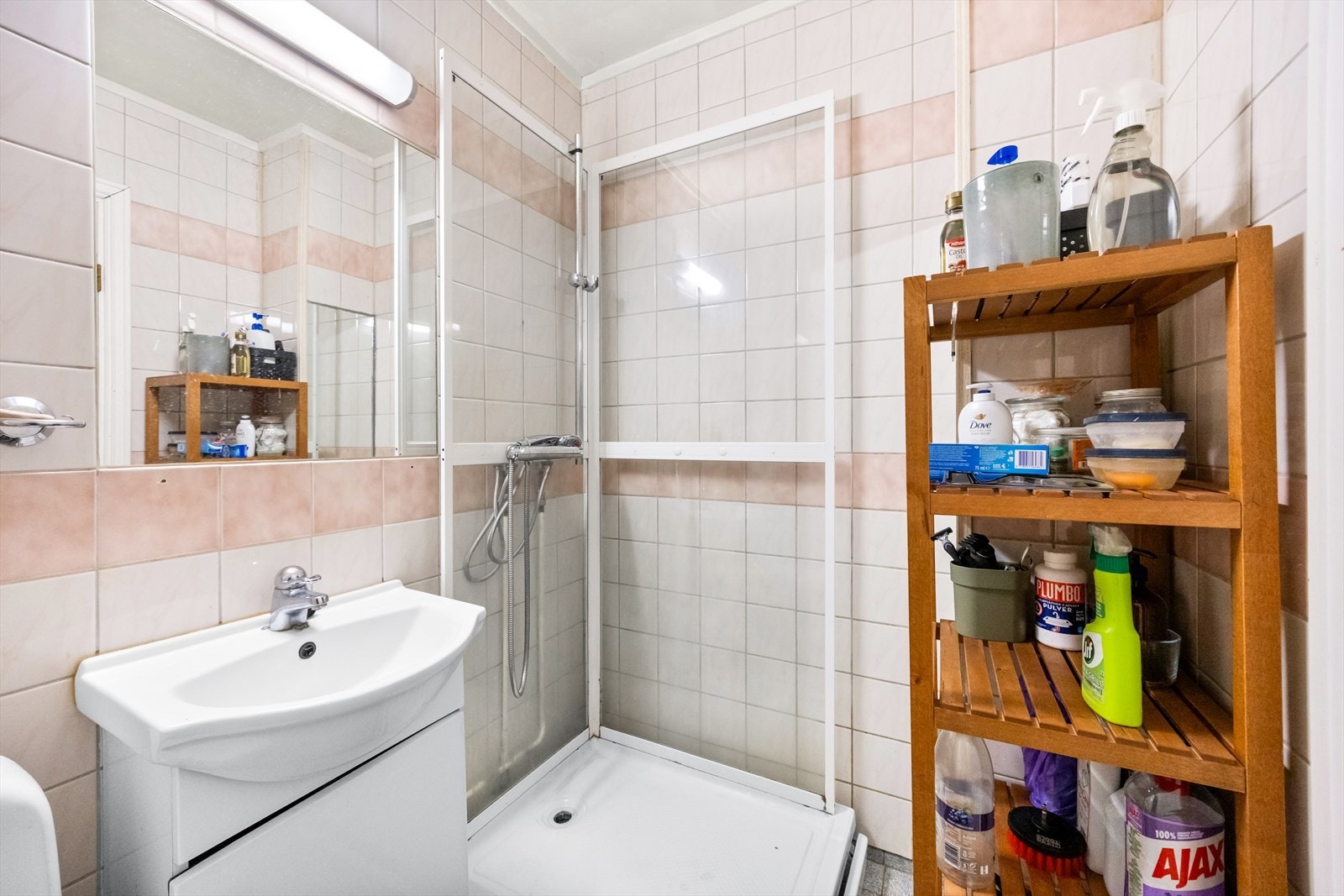 Badet har flislagte overflater og er innredet med servant med underskap og dusjkabinett. Galleribilde