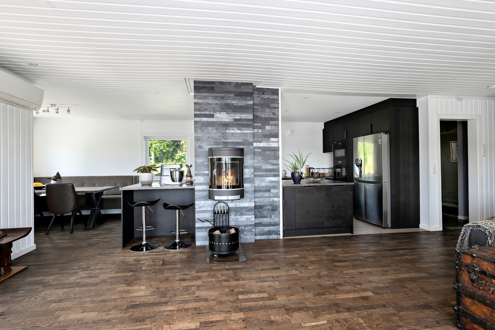 Her er kjøkkenet smart plassert i et eget hjørne som skaper et naturlig skille mellom oppholdsrom og matlagingssonen, samtidig som det åpner for sosialt samvær på tvers av rommet. Galleribilde