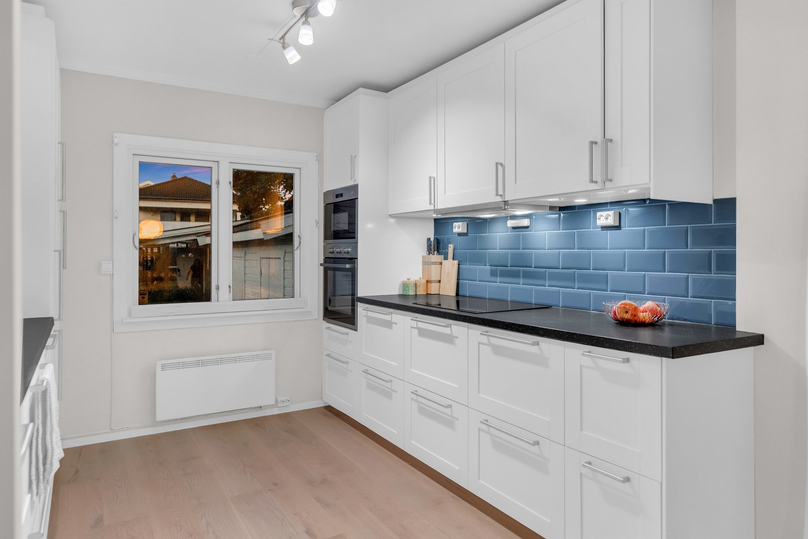 Kjøkken med integrerte hvitevarer som stekeovn og mikro i høyskap, nedfeldt steketopp, kjøleskap og oppvaskmaskin Galleribilde