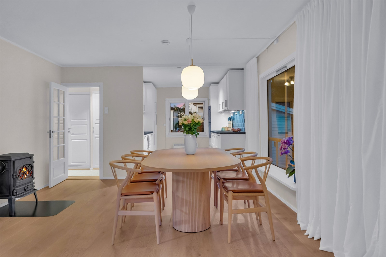 Moderne kjøkken med tilknytning til spiseplass foran vindu mot hagen Galleribilde