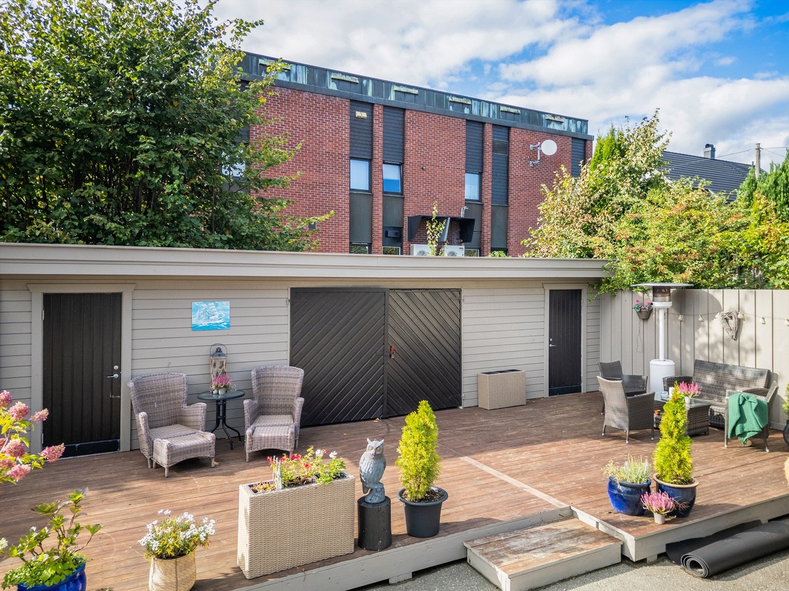 Felles bakgård som er opparbeidet med platting som er pent møblert med flere sitteplasser og grill Galleribilde