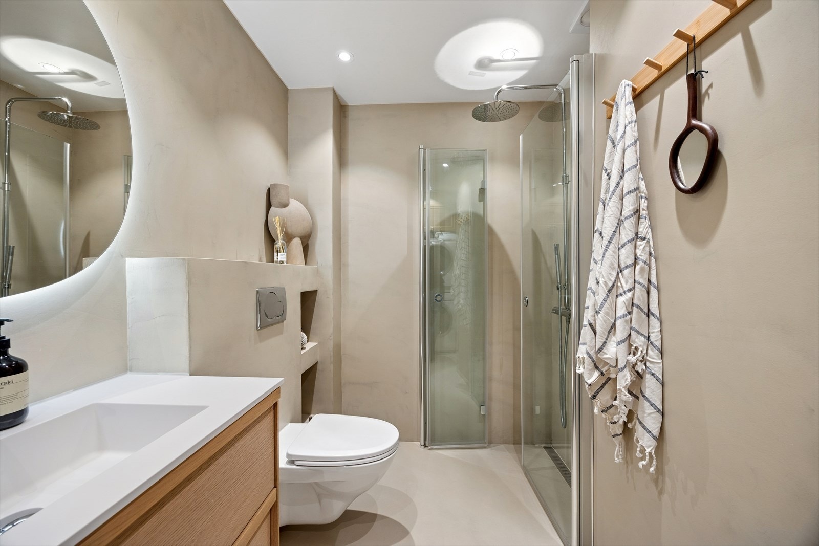 Badet er innredet med servantskap med ettgreps blandebatteri, veggspeil med integrert belysning, vegghengt toalett med innebygd sisterne, høyskap samt et avskjermet dusjhjørne med glassvegger. Dusjsonen er utstyrt med linjesluk og uttakbar vannlås. Galleribilde