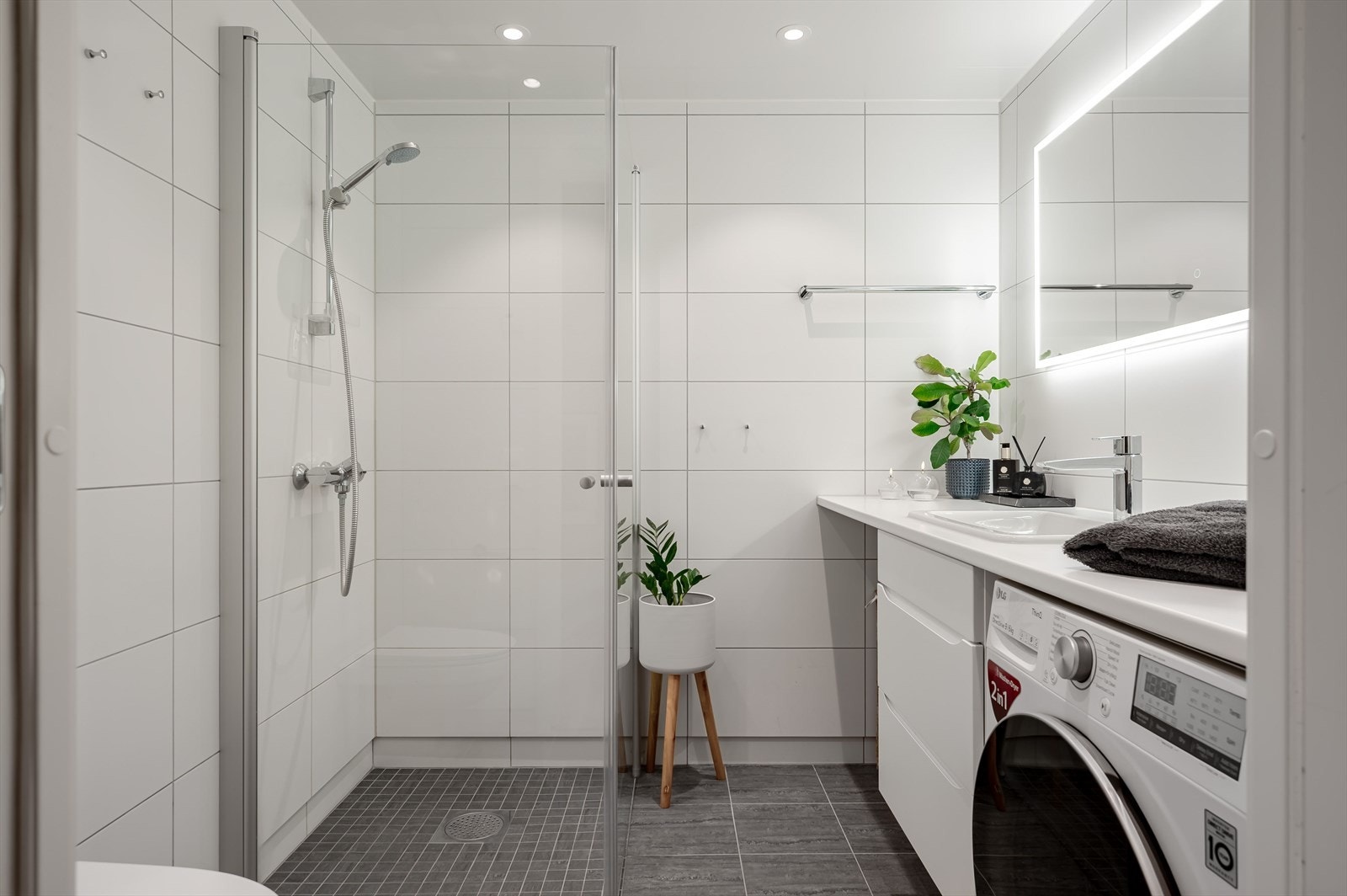 Badet er flislagt og inneholder hjørnedusj, servant, vegghengt toalett og opplegg for vaskemaskin. Galleribilde