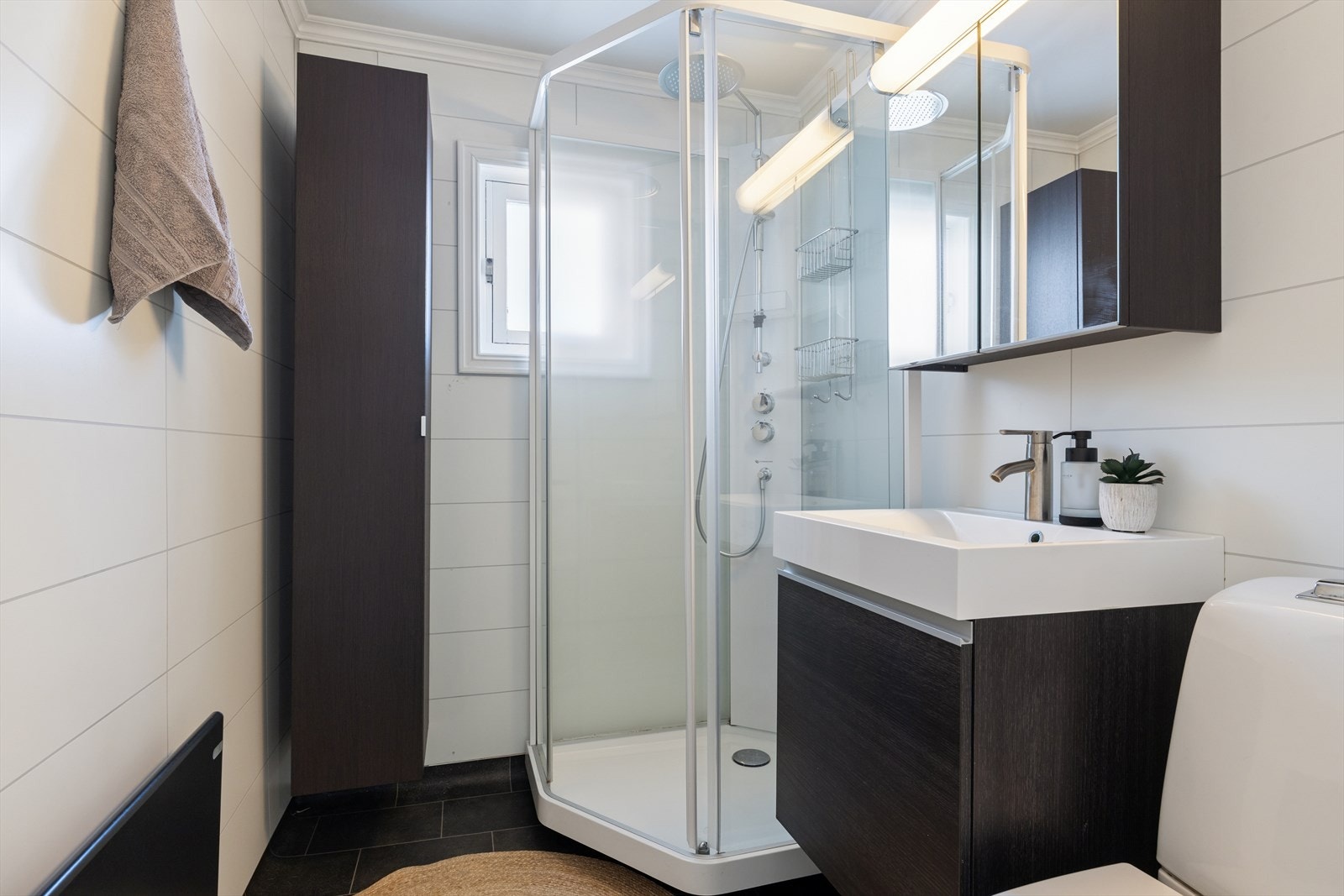 Badet ble også oppgradert i 2014. Rommet har vinylbelegg på gulvet, baderomsplater på veggene og malte plater i himlingen. Innredningen består av servantskap, toalett og et praktisk dusjkabinett (2020). Ventilasjonen er mekanisk. Galleribilde