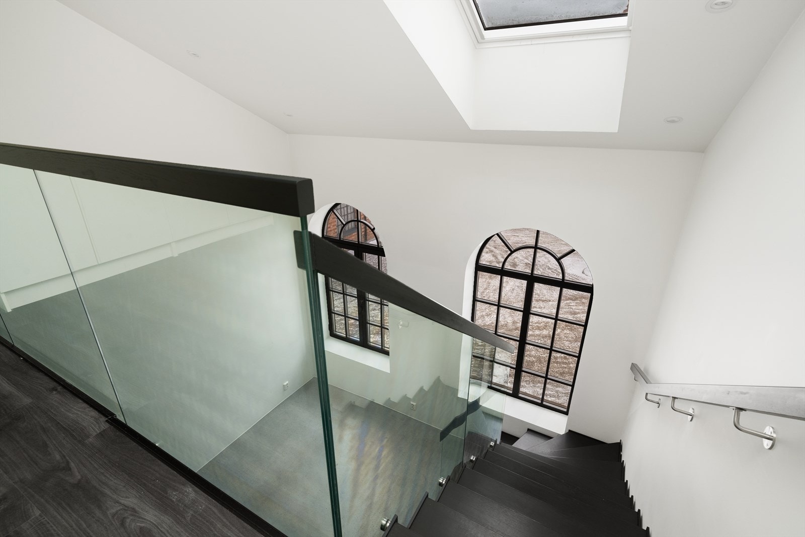 Fra stuen er det lakkert tretrapp med glassrekkverk opp til mesanin. Galleribilde